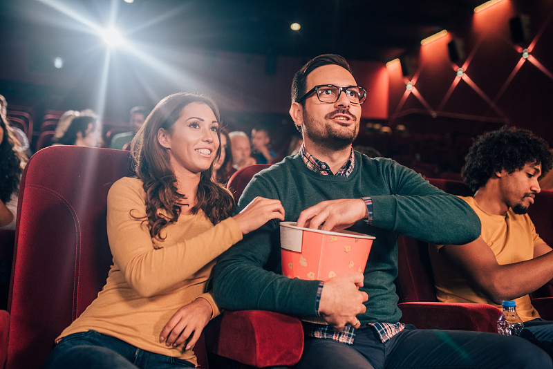 一对情侣在电影院分享一袋爆米花图片素材