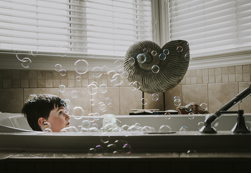男孩在浴缸洗澡时看泡泡图片素材