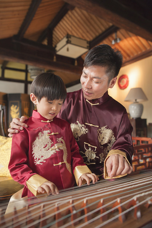 中国的父亲和儿子在传统服装演奏竖琴图片下载