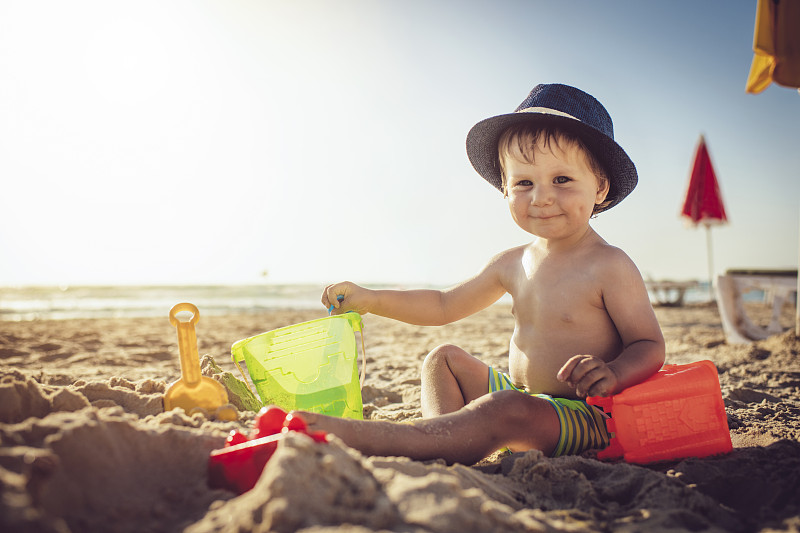 小男孩坐在沙滩上，在堆沙堡图片下载