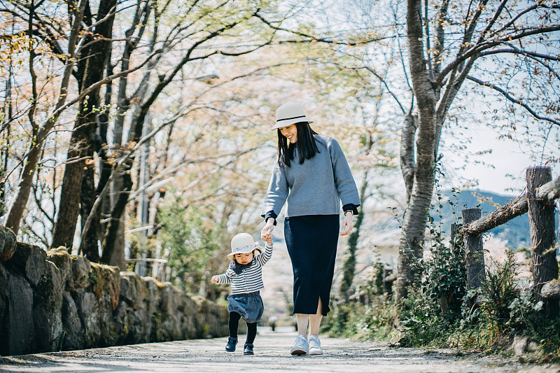 慈爱的年轻亚洲母亲牵着可爱的小女儿在自然的小路上散步，享受亲密的家庭时光图片下载