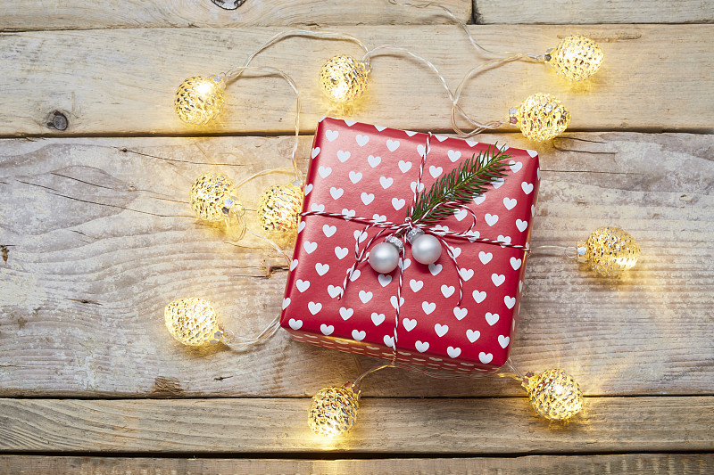 高角度的包装圣诞礼物和圣诞灯在木制桌子上图片下载