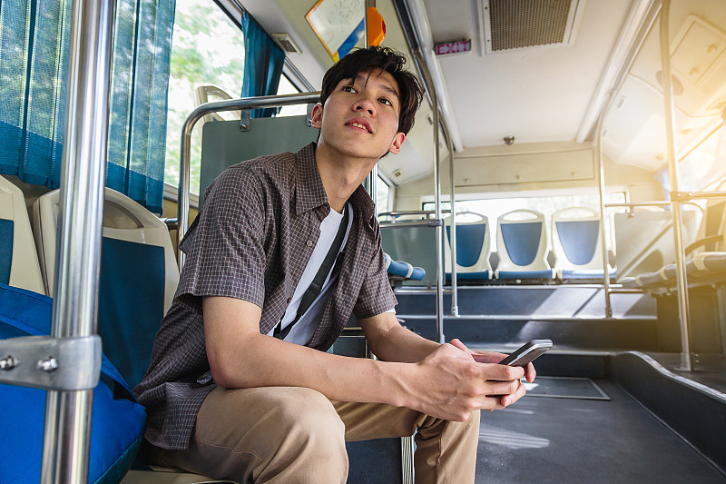 年轻的亚洲旅行者喜欢乘巴士旅行和使用手机图片下载