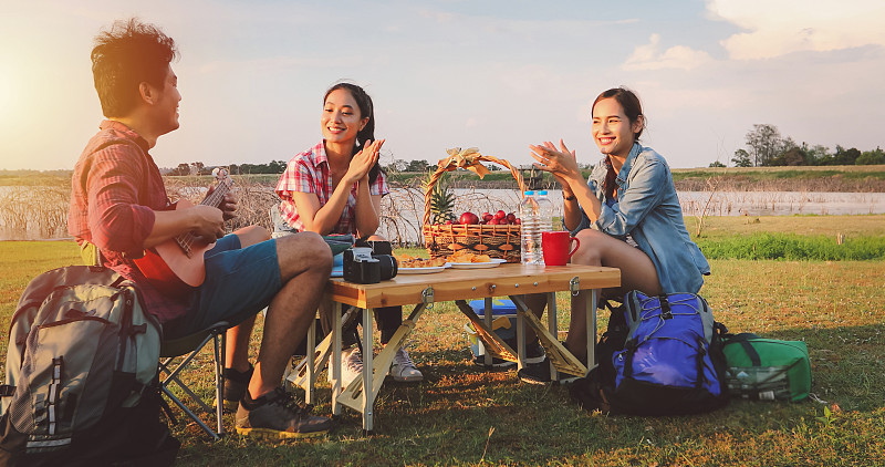 一群亚洲朋友玩尤克里里和花时间在夏季假期野餐。他们在假期很快乐，玩得很开心。图片下载