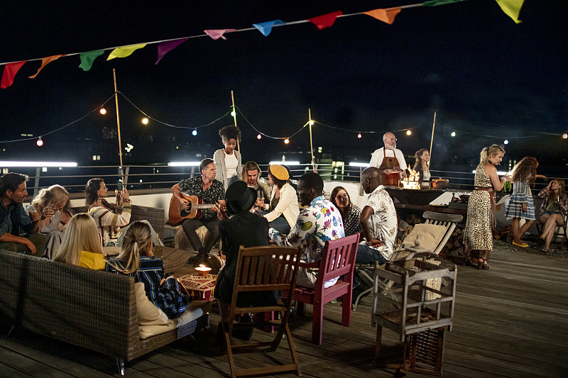 一大群朋友坐在一起享受夏季城市屋顶派对在慕尼黑图片下载