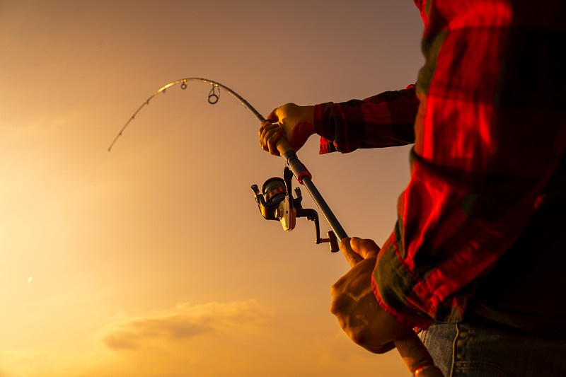 日落时在湖上钓鱼。钓鱼的背景。图片下载