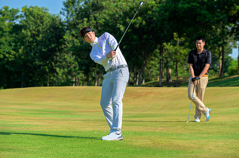亚洲高尔夫球手在高尔夫球场上击球图片下载