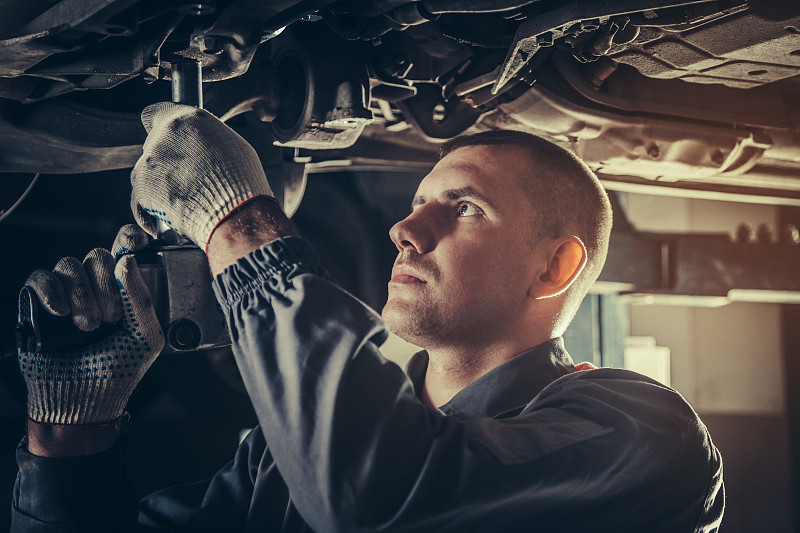 在汽车修理厂修理汽车的专业机械师图片下载