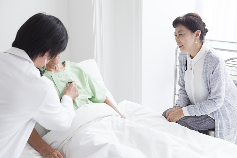 一位医生告诉一位住院的老人病情。一个在旁边倾听的妻子。图片素材