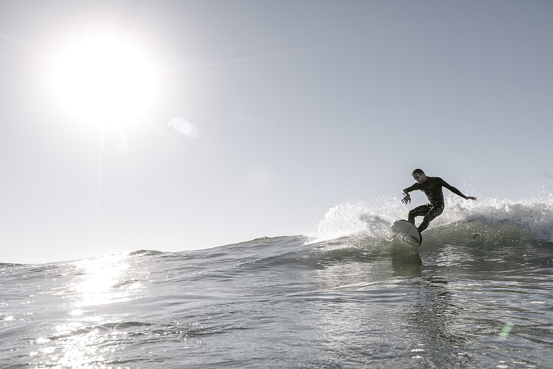 在晴朗的日子里，一个中年人在大海的巨浪上冲浪图片下载