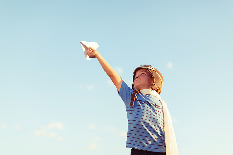 装扮成飞行员的小男孩驾驶着纸飞机图片素材