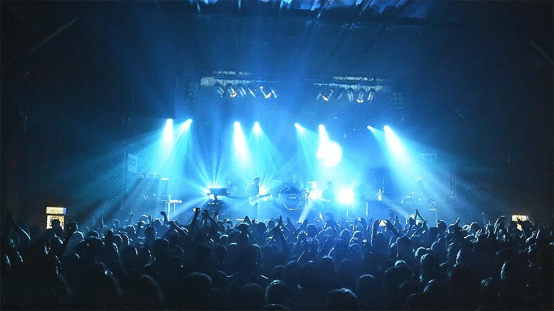 人群在音乐会与蓝色舞台灯光图片下载