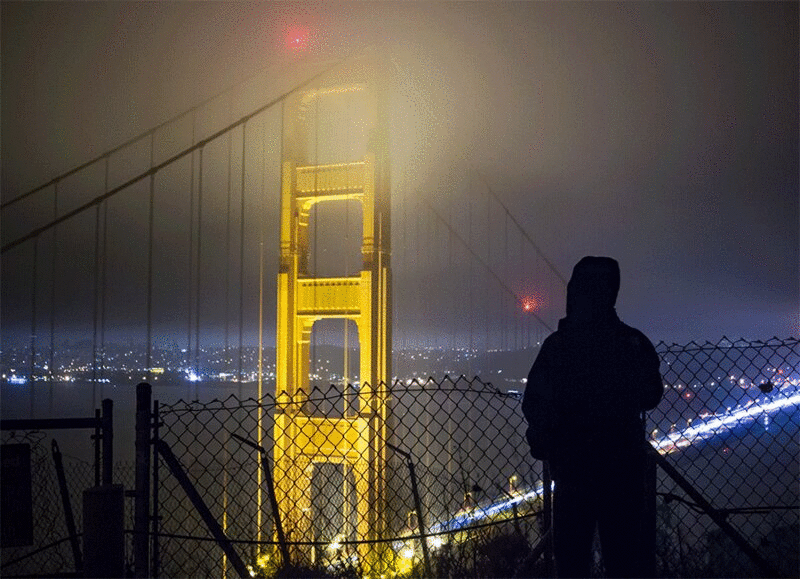 美国旧金山，加利福尼亚，金门大桥上的人在晚上看着交通的后视图剪影图片下载