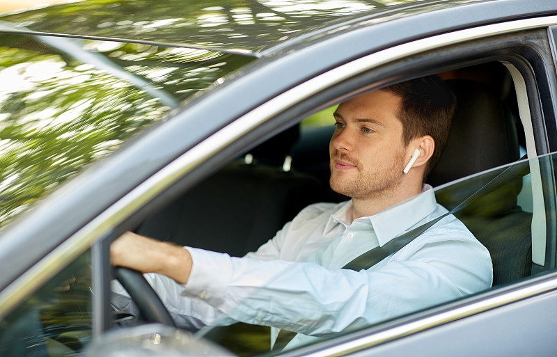 交通，车辆和人的概念-人或司机与无线耳机或免提设备驾驶汽车。带无线耳机驾驶汽车的人或司机图片素材