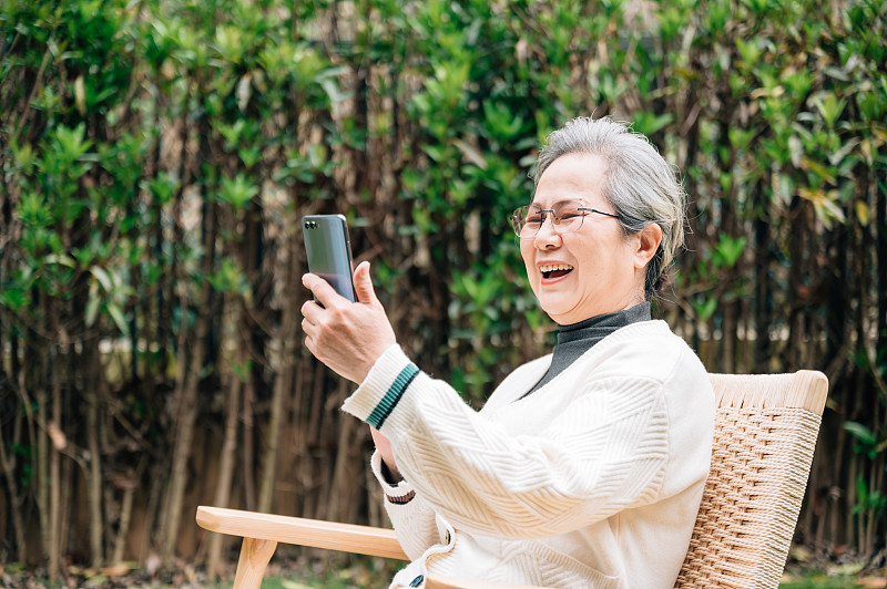 亚洲老年女性使用智能手机图片下载