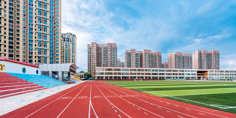 体育场的红色跑道和远处的高楼建筑图片下载