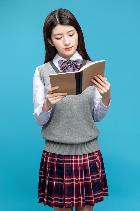 蓝色背景里拿着书本的中国女学生图片素材