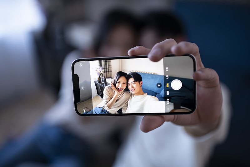 年轻情侣在家使用智能手机自拍图片素材