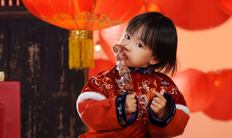 可爱的小男孩拿着糖葫芦庆新年图片下载
