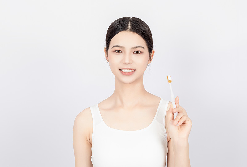 白色背景中一名亚洲年轻美女在刷牙图片下载