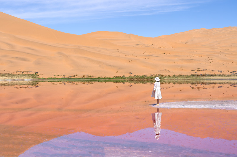 女性游客在中国西部内蒙古阿拉善右旗巴丹吉林沙漠粉红湖的旅拍写真图片下载