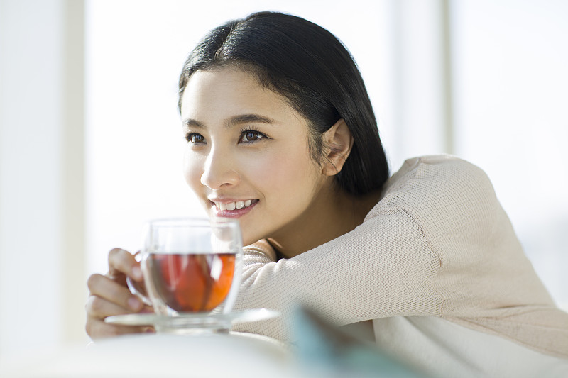 快乐的年轻女子喝红茶图片下载