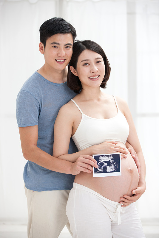 年轻夫妇拿着胎儿B超照片摄影图片下载