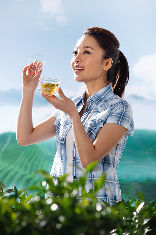 一个东方青年女人在茶园喝茶图片素材