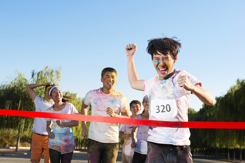 Young man crossing finishing line at The Color Run图片下载