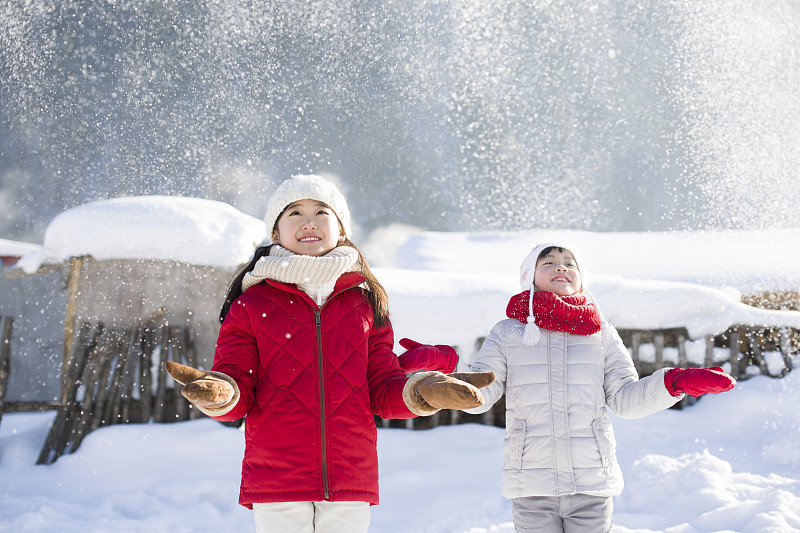 两个女孩伸手接飘落的雪花图片下载