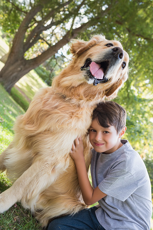 一个阳光明媚的日子，一个小男孩和他的狗在公园里图片下载