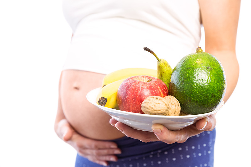 孕妇在白色背景上显示水果和蔬菜图片素材