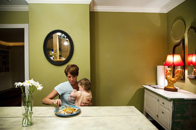 母亲和女儿(6-12个月)在家吃饭图片素材