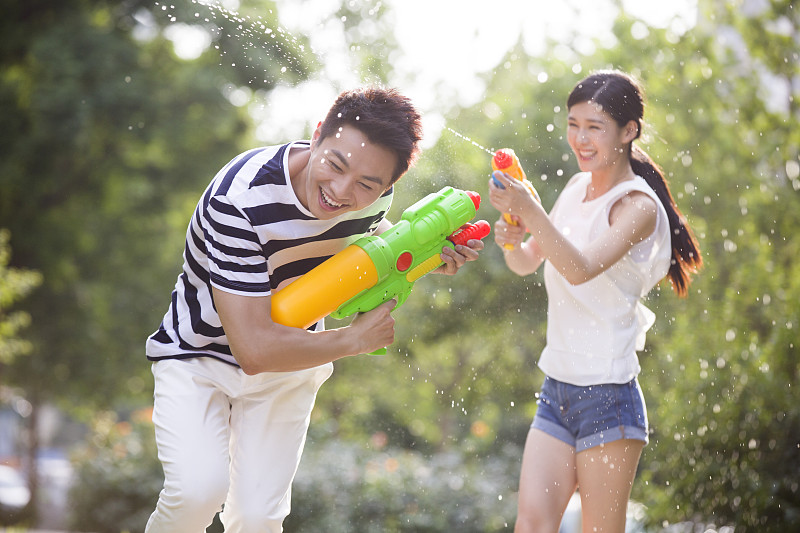 快乐的年轻情侣玩水枪图片下载