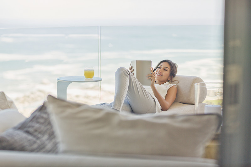 女人放松阅读在豪华阳台上的躺椅与海洋的vie图片素材