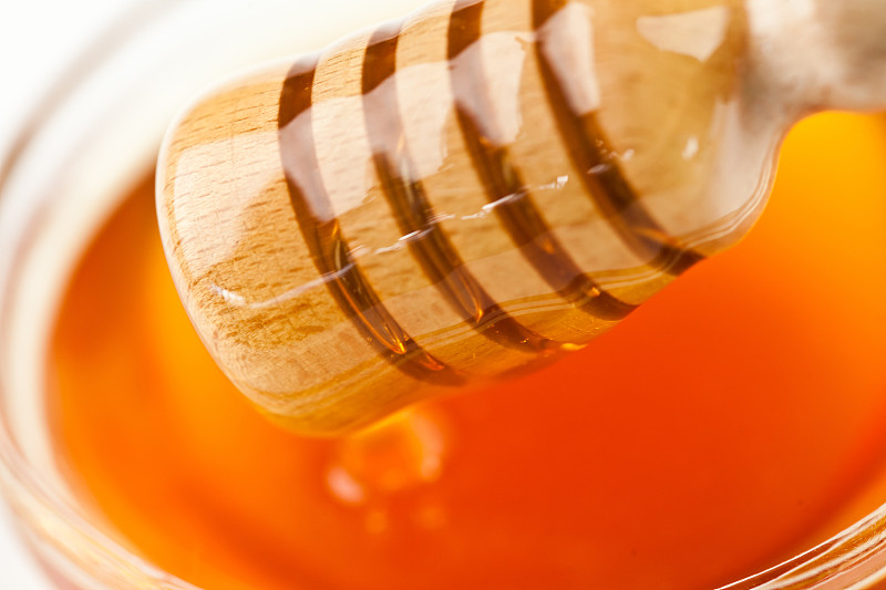 蜂蜜舀出一个蜂蜜碗在白色的背景图片素材