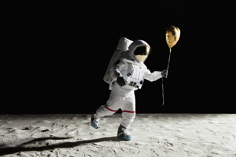 一个宇航员在月球上拿着一个心形的氦气球图片下载