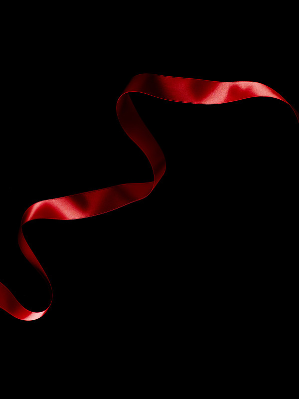 黑色背景上流动的红丝带。图片素材