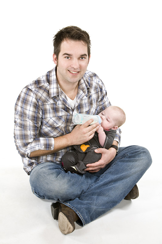 年轻的成年父亲正在给膝上的女婴喂奶图片下载