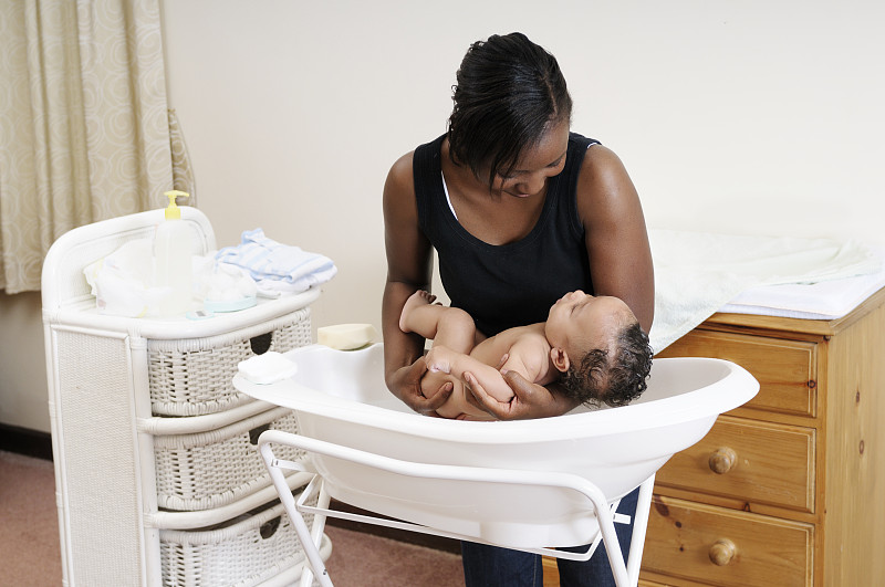 一位非裔美国妇女正在把婴儿放进浴缸里图片素材