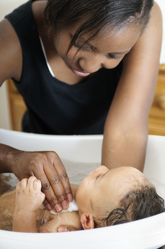 非裔美国妇女洗婴儿-近距离观看图片素材