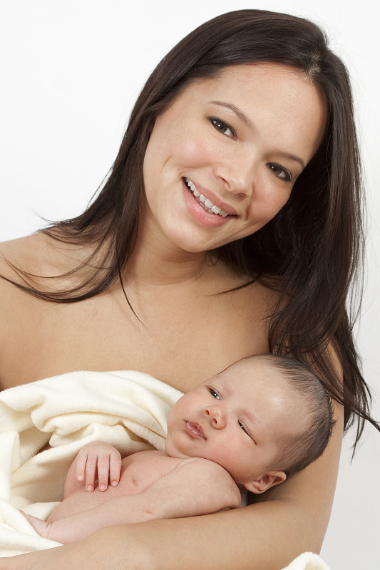 年轻的混血妇女抱着婴儿，面带微笑图片下载