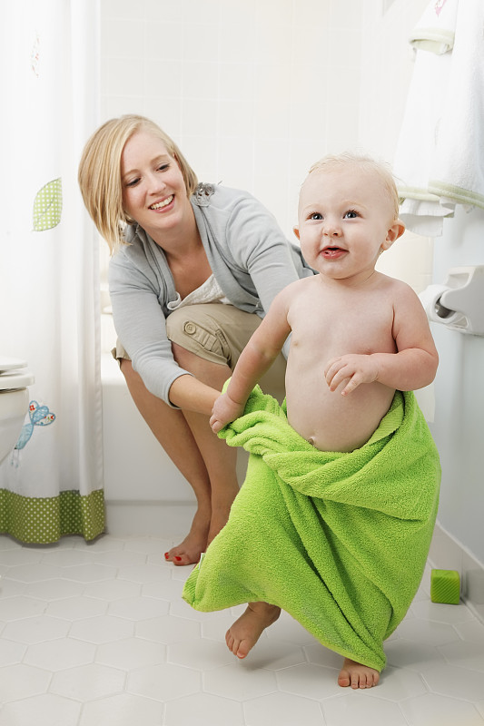 微笑的年轻母亲和顽皮的孩子在洗澡时间。图片下载