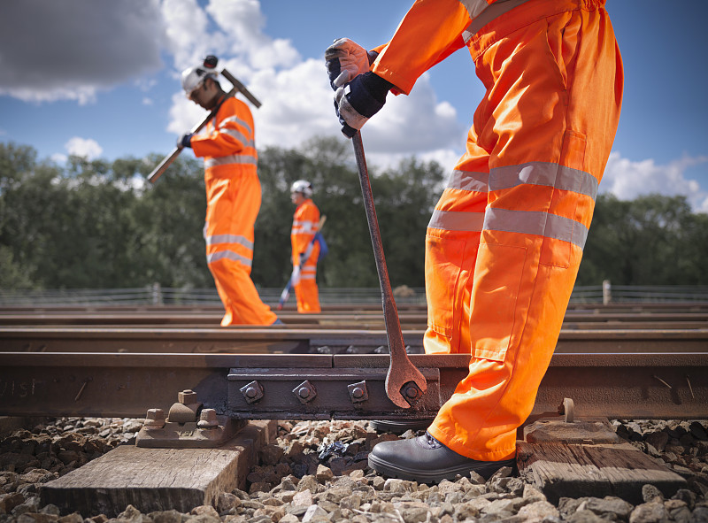 铁路工人穿着高能见度服装修理铁路轨道侧视图图片下载