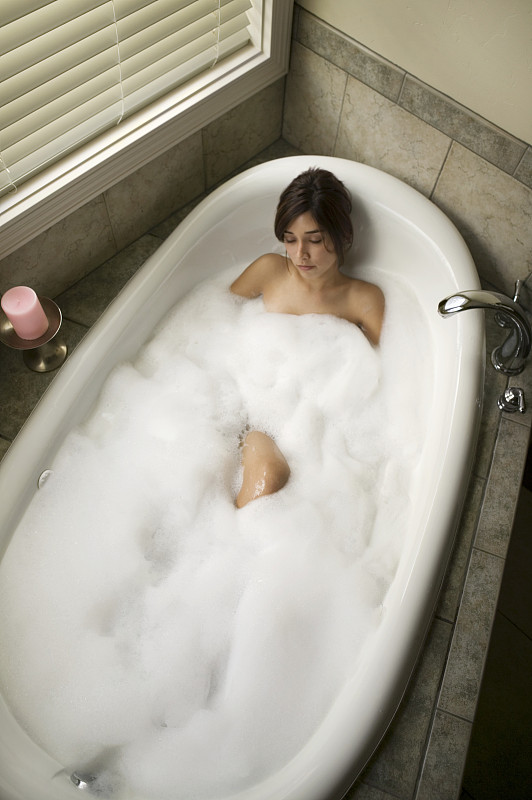 年轻女子在浴缸里放松，俯瞰高处图片下载