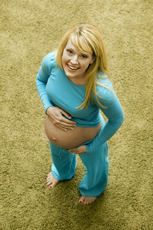 孕妇站在外面，抚摸着肚子，高视阔步图片下载