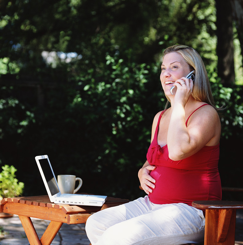 孕妇坐在外面，用手提电脑打手机图片下载