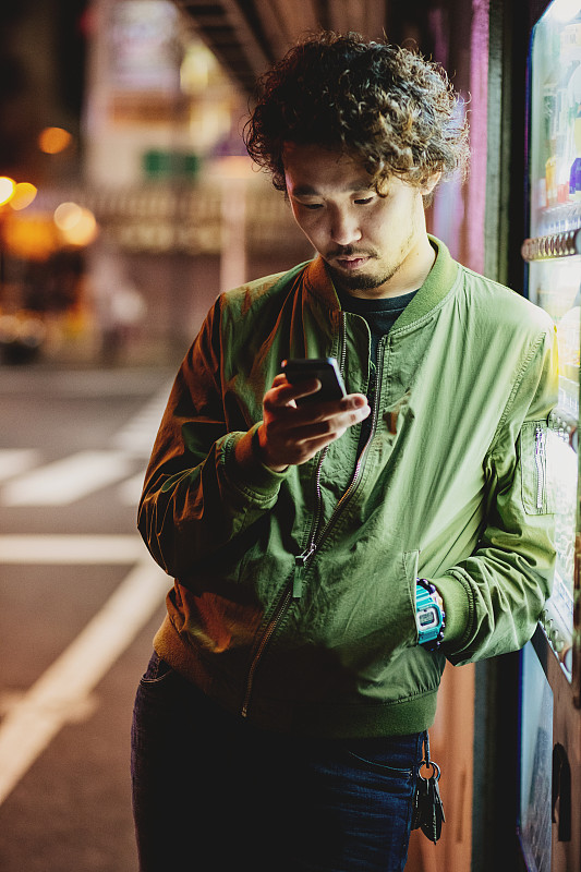 年轻的日本青少年在城市场景中拿着手机图片下载
