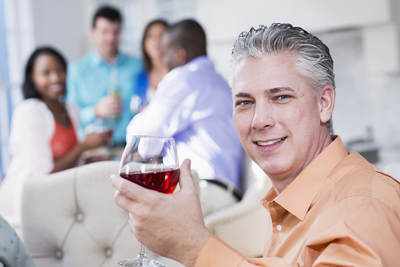 成熟的男人在派对上喝着红酒图片下载