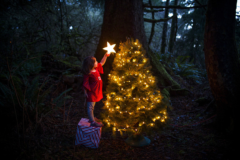 一个高加索女孩在森林里装饰圣诞树图片下载